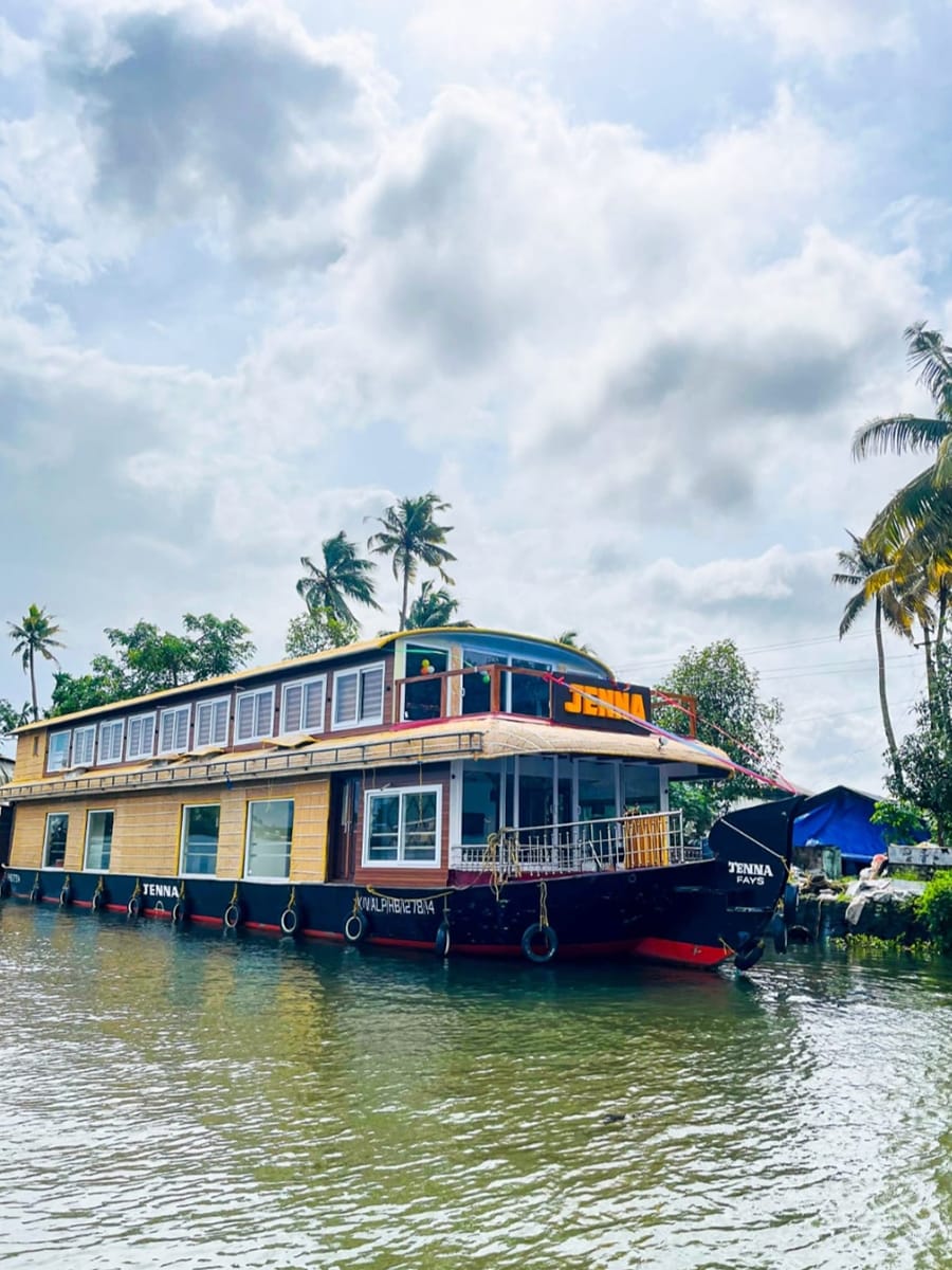 Exterior daytime view of a 4 bedroom premium houseboat with full upper deck cruising on Alleppey backwaters.