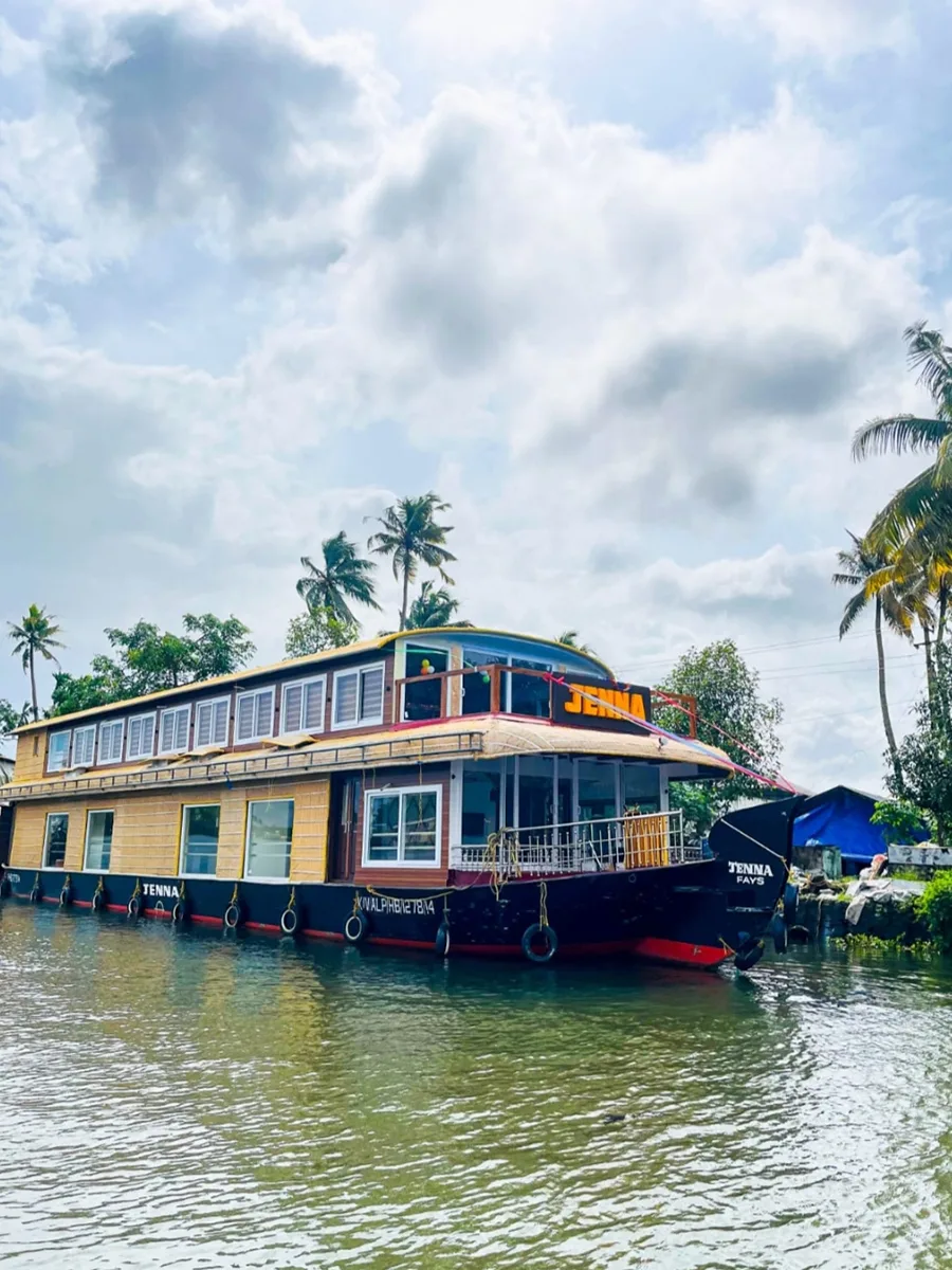 Exterior daytime view of a 4 bedroom premium houseboat with full upper deck cruising on Alleppey backwaters.