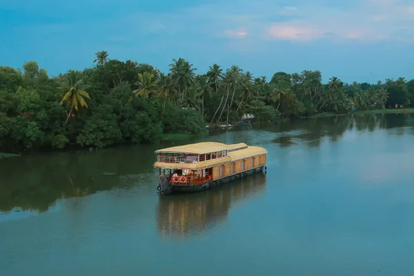 Alleppey Houseboat Booking Guide for First-Time Travellers A private premium glass-enclosed Alleppey boathouse cruising the Kuttanad backwaters in Kerala India.
