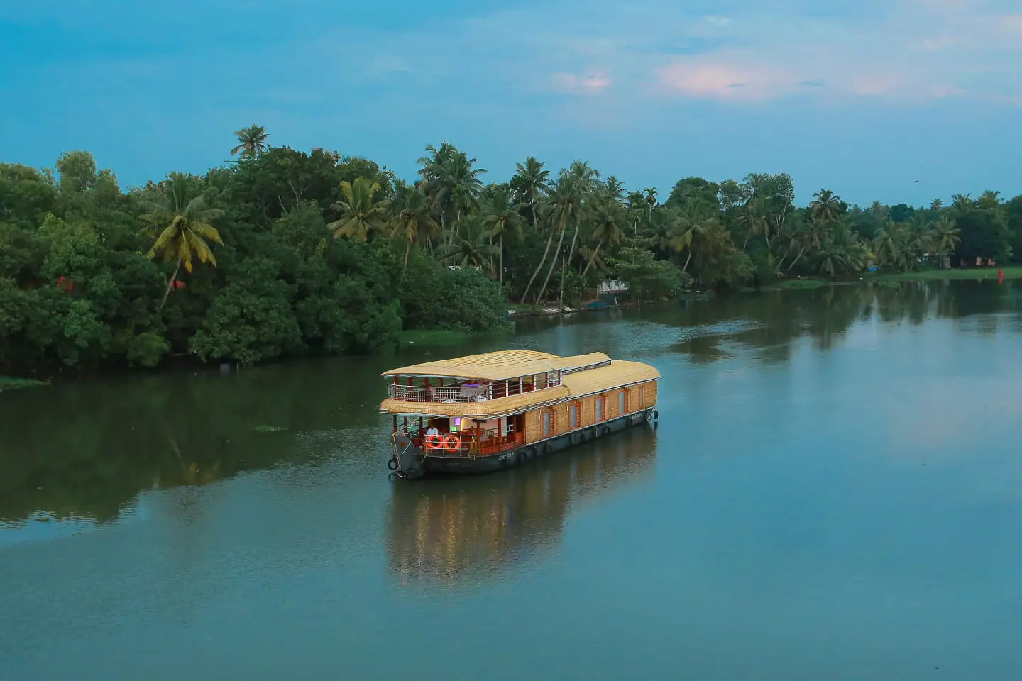 A private premium glass-enclosed Alleppey boathouse cruising the Kuttanad backwaters in Kerala India.