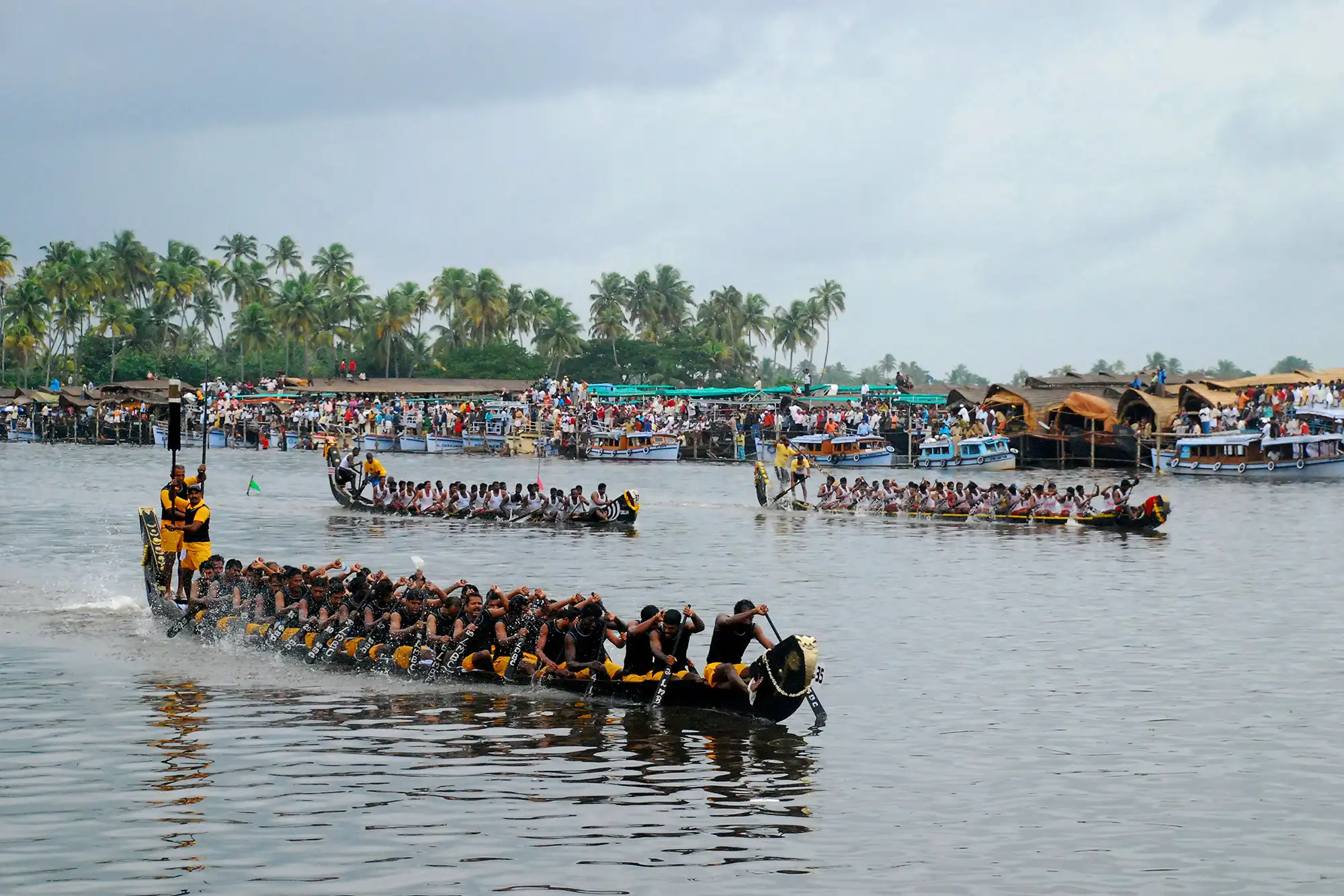 A premium double deck Alleppey boathouse anchored on Punnamada Lake watching the Nehru Trophy Snake Boat Race during Onam season in Kerala India.