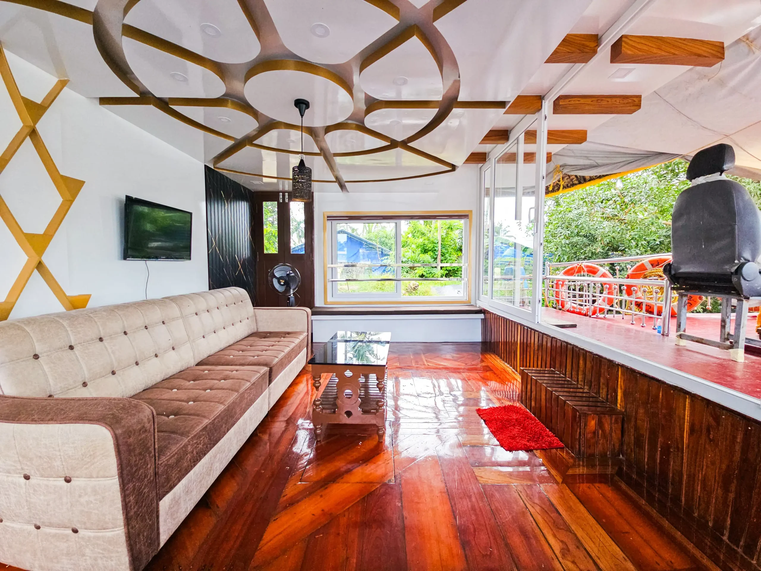 Air-Conditioned Front Lounge Sitting Area – Houseboat Fully air-conditioned lower deck front lounge with plush sofa seating and wooden flooring inside a 4 bedroom houseboat.