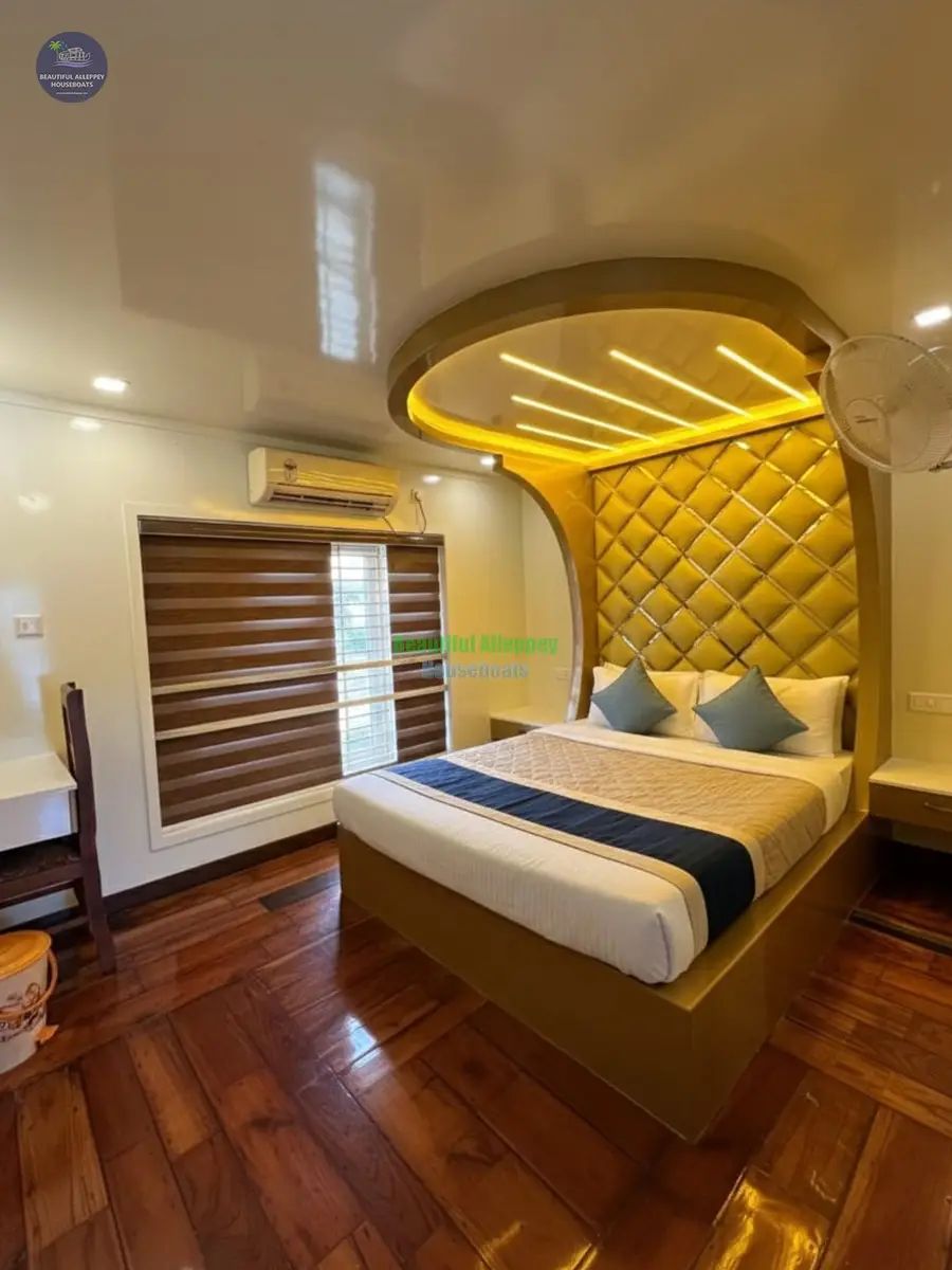 Premium AC Bedroom with Wooden Flooring – 4 Bed Houseboat Premium double bed with yellow ambient canopy light, side table, and polished timber flooring inside a houseboat.