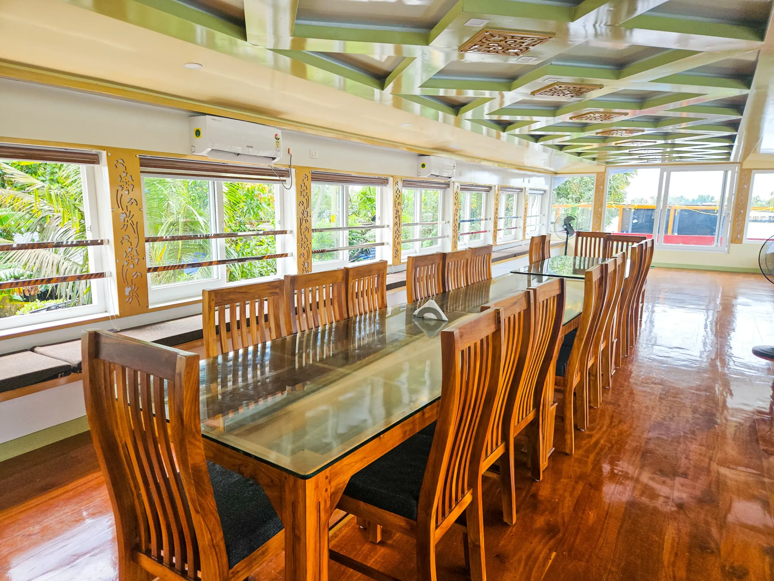 Glass-Enclosed Upper Deck Dining Hall – 4 Bedroom Houseboat Spacious glass-enclosed upper deck dining area with long wooden table and chairs inside a 4 bedroom premium houseboat.