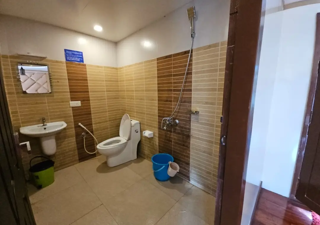 En-Suite Bathroom with Modern Fixtures – 4 Bed Houseboat Attached bathroom with modern wall tiles, mirror, sink, and western toilet inside a premium houseboat.