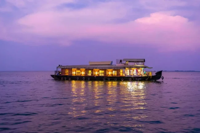 Traditional private Alleppey houseboat cruising along palm-fringed backwater channels in Kerala