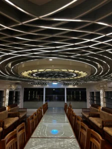 Night view of the glass-enclosed upper deck on a 5 bedroom luxury houseboat in Alleppey glowing with modern ambient LED lighting.