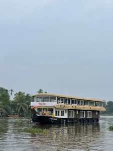 Full exterior daytime view of Kingster 5 bedroom premium AC houseboat with upper deck cruising on Alleppey backwaters.