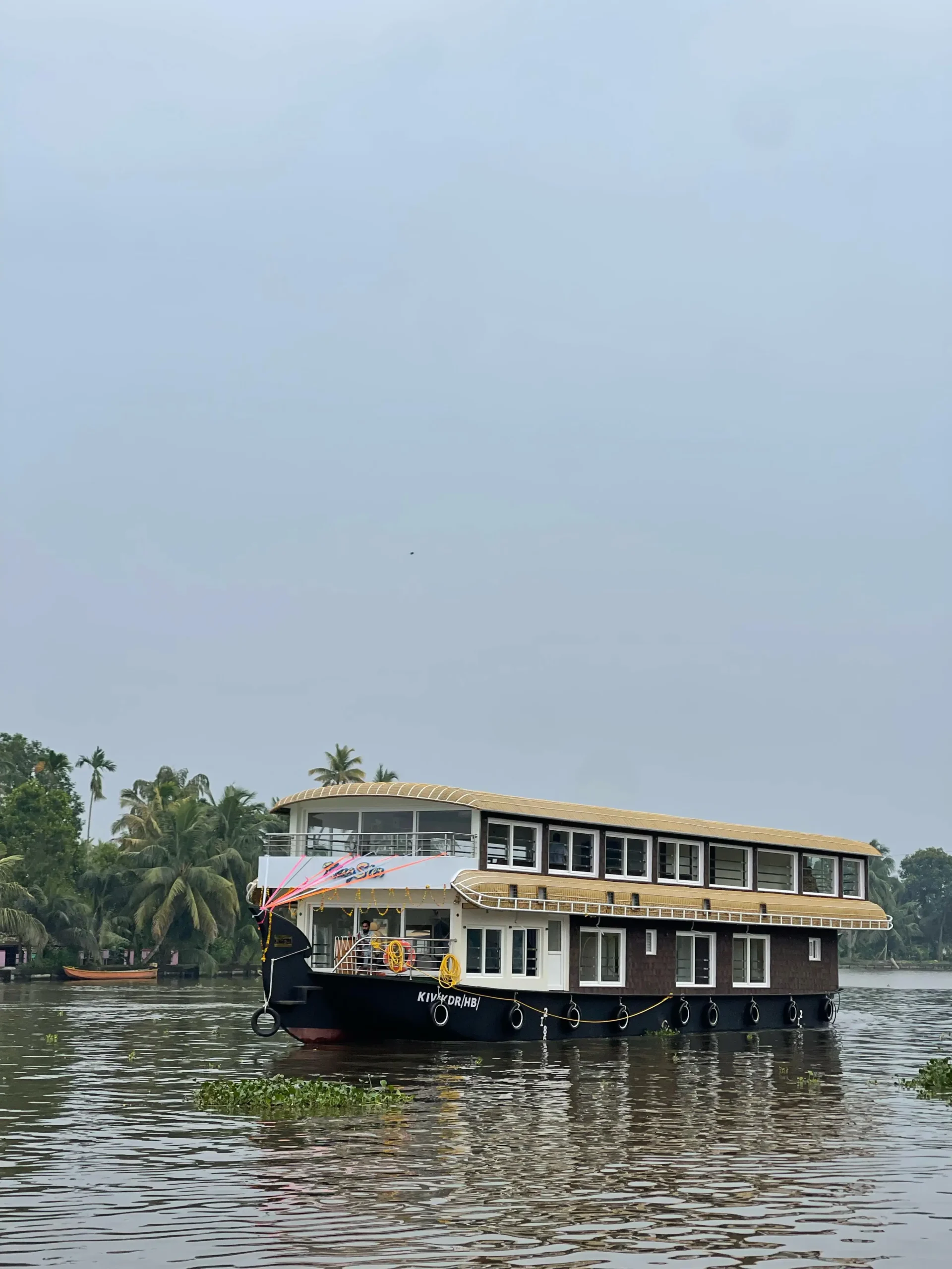 Full exterior daytime view of Kingster 5 bedroom premium AC houseboat with upper deck cruising on Alleppey backwaters.