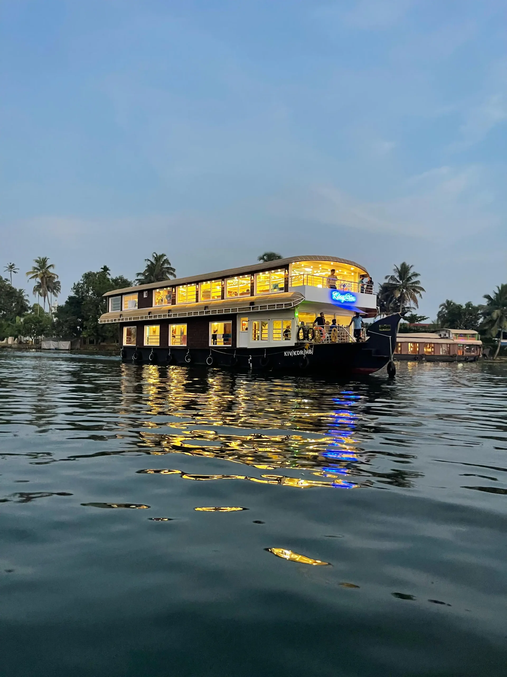 Kingster 5 Bedroom Houseboat Night View with Exterior LED Lights Night exterior view of the fully illuminated 5 bedroom Kingster luxury houseboat anchored on the Kerala backwaters.