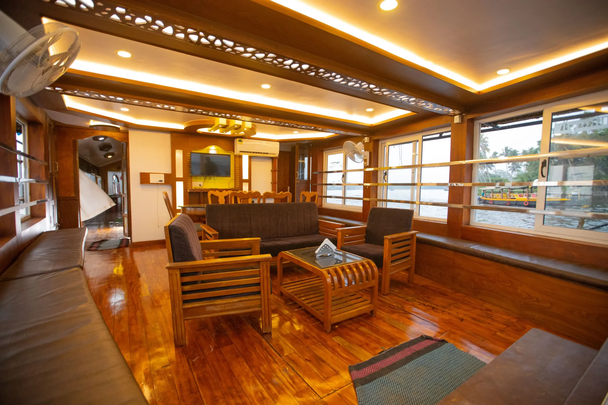 mithtam-mithram02-front-glass-covered-ac-lounge-dining Front glass-enclosed air-conditioned lounge and dining area on Mithtam premium houseboat overlooking backwaters.